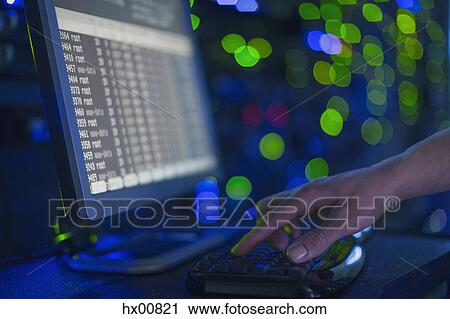 Stock Image - Server room technician using computer. Fotosearch