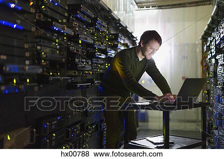 Server room technician working at laptop View Large Photo Image Stock Photo - Server room technician working at laptop. Fotosearch