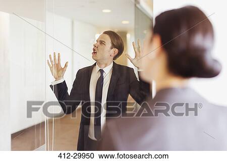 Silly businessman pressing face against office glass View Large Photo Image Stock Image - Silly businessman pressing face against office glass. Fotosearch