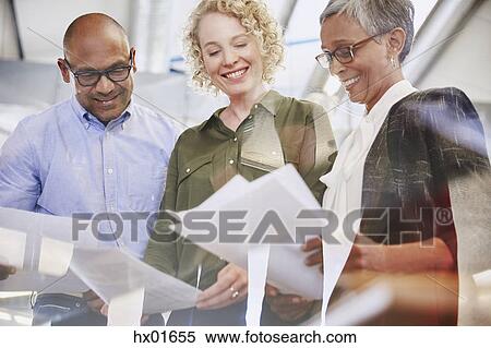Smiling business people discussing paperwork in meeting View Large Photo Image Stock Photography - Smiling business people discussing paperwork in meeting. Fotosearch