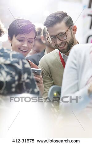 Smiling business people texting at technology conference View Large Photo Image Stock Photography - Smiling business people texting at technology conference. Fotosearch