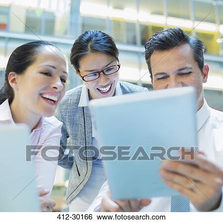 Stock Photograph - Smiling business people using digital tablet in office. Fotosearch