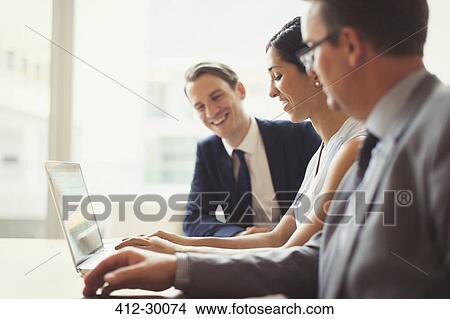 Picture - Smiling business people using laptop in conference room. Fotosearch