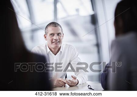 Stock Photo - Smiling businessman listening in meeting. Fotosearch