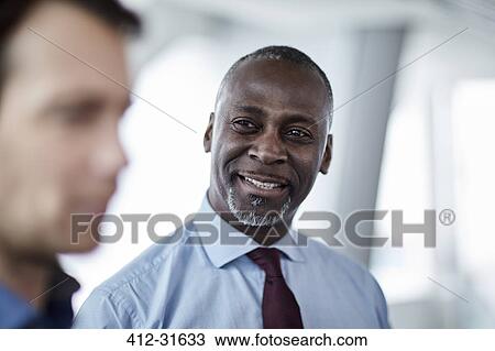 Stock Image - Smiling businessman listening to colleague. Fotosearch