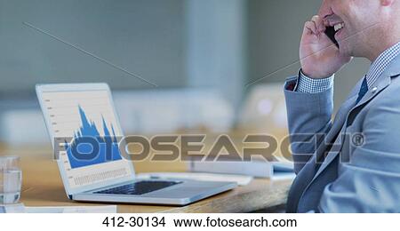 Picture - Smiling businessman talking on cell phone at laptop in conference room. Fotosearch