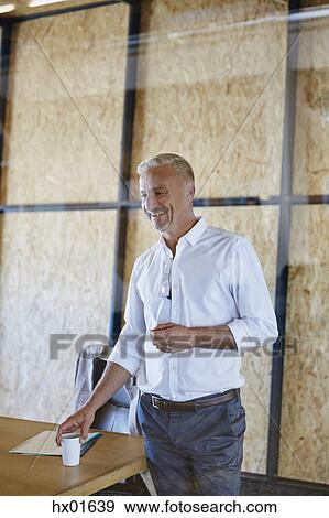 Smiling businessman with coffee in conference room View Large Photo Image Stock Photo - Smiling businessman with coffee in conference room. Fotosearch