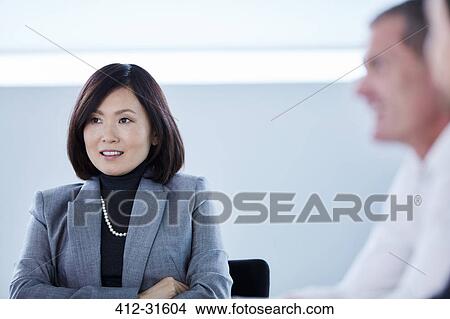 Picture - Smiling businesswoman listening in meeting. Fotosearch