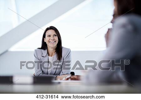 Picture - Smiling businesswoman listening in meeting. Fotosearch
