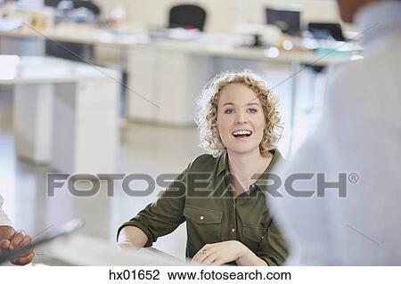 Stock Image - Smiling businesswoman listening in meeting. Fotosearch