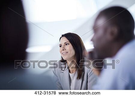 Stock Photo - Smiling businesswoman listening in meeting. Fotosearch