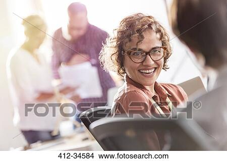 Smiling businesswoman listening to colleague in office View Large Photo Image Picture - Smiling businesswoman listening to colleague in office. Fotosearch