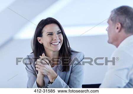 Smiling businesswoman listening to businessman in meeting View Large Photo Image Stock Photography - Smiling businesswoman listening to businessman in meeting. Fotosearch