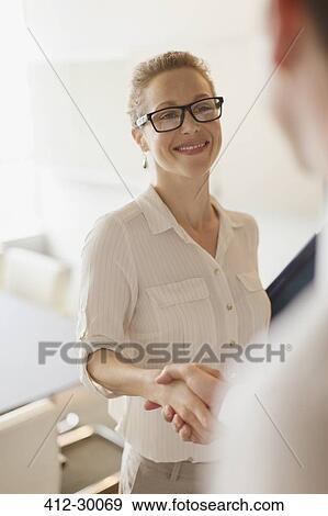 Stock Photo - Smiling businesswoman shaking hands with businessman. Fotosearch