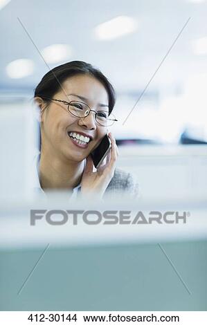 Smiling businesswoman talking on telephone in office View Large Photo Image Picture - Smiling businesswoman talking on telephone in office. Fotosearch