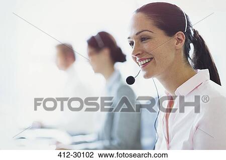 Smiling businesswoman talking on the phone with headset View Large Photo Image Stock Image - Smiling businesswoman talking on the phone with headset. Fotosearch