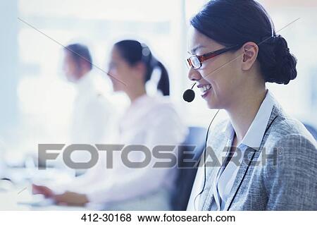 Smiling businesswoman talking on the phone with headset View Large Photo Image Stock Photo - Smiling businesswoman talking on the phone with headset. Fotosearch