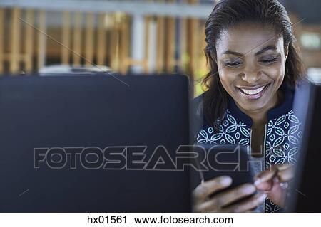 Stock Image - Smiling businesswoman texting with cell phone. Fotosearch