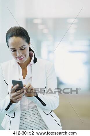 Smiling businesswoman using cell phone in office corridor View Large Photo Image Stock Image - Smiling businesswoman using cell phone in office corridor. Fotosearch
