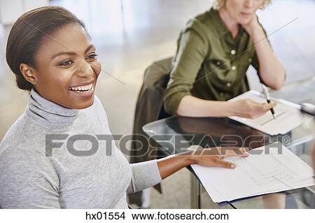 Picture - Smiling businesswoman with paperwork in meeting. Fotosearch