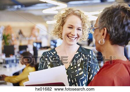 Smiling businesswomen talking in office View Large Photo Image Stock Image - Smiling businesswomen talking in office. Fotosearch