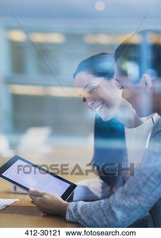 Stock Image - Smiling businesswomen using digital tablet in office. Fotosearch