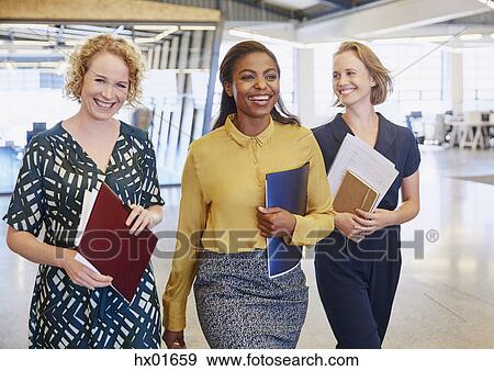 Stock Photo - Smiling businesswomen walking in office. Fotosearch