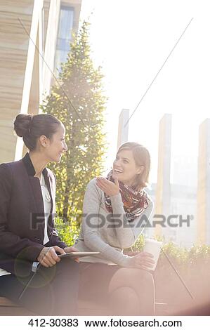 Smiling businesswomen with digital tablet and coffee talking in city park View Large Photo Image Stock Image - Smiling businesswomen with digital tablet and coffee talking in city park. Fotosearch