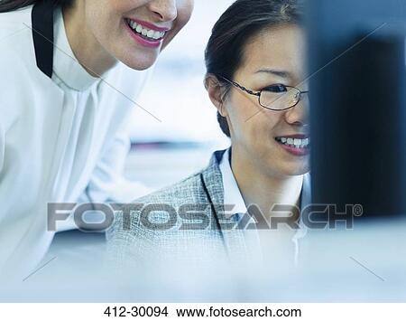 Smiling businesswomen working at computer in office View Large Photo Image Picture - Smiling businesswomen working at computer in office. Fotosearch