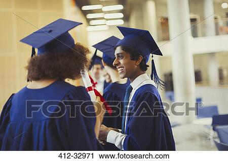 Stock Image - Smiling college graduates in cap and gown. Fotosearch