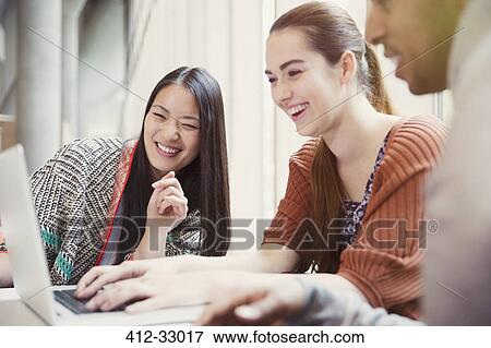 Smiling college students using laptop View Large Photo Image Stock Photo - Smiling college students using laptop. Fotosearch