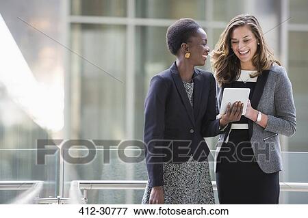 Smiling corporate businesswomen using digital tablet View Large Photo Image Stock Photo - Smiling corporate businesswomen using digital tablet. Fotosearch