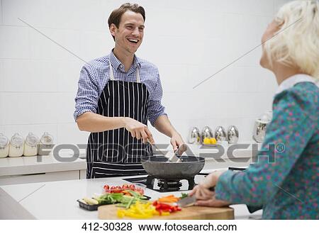 Smiling couple cutting and cooking vegetables in kitchen View Large Photo Image Stock Photo - Smiling couple cutting and cooking vegetables in kitchen. Fotosearch