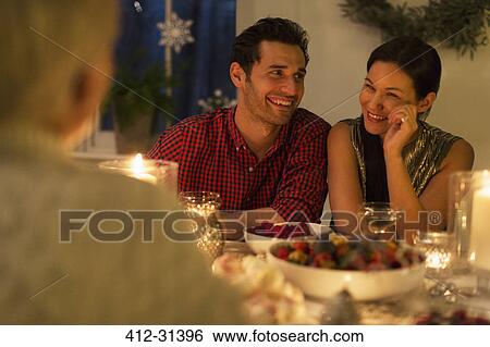Smiling couple enjoying candlelight Christmas dinner View Large Photo Image Stock Photograph - Smiling couple enjoying candlelight Christmas dinner. Fotosearch