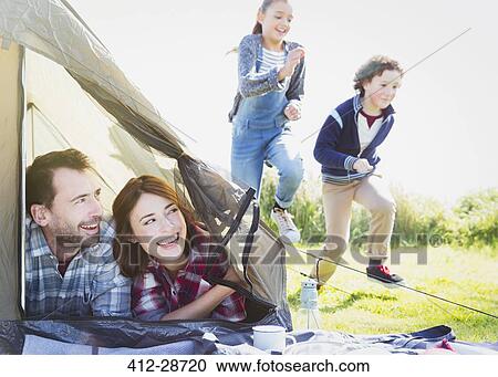 Smiling couple in tent watching kids running in grass View Large Photo Image Stock Image - Smiling couple in tent watching kids running in grass. Fotosearch