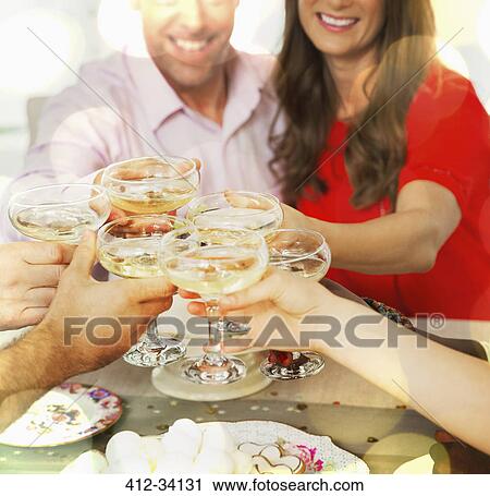 Smiling couple toasting champagne glasses with friends at table View Large Photo Image Stock Image - Smiling couple toasting champagne glasses with friends at table. Fotosearch