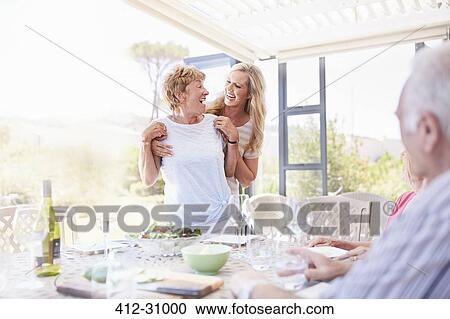 Smiling daughter hugging senior mother at patio lunch View Large Photo Image Stock Image - Smiling daughter hugging senior mother at patio lunch. Fotosearch