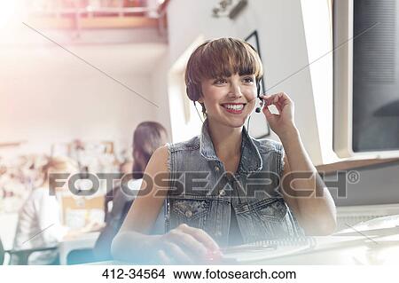 Picture - Smiling design professional using headset with microphone in office. Fotosearch