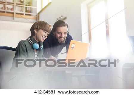 Smiling design professionals meeting at laptop in office View Large Photo Image Stock Image - Smiling design professionals meeting at laptop in office. Fotosearch