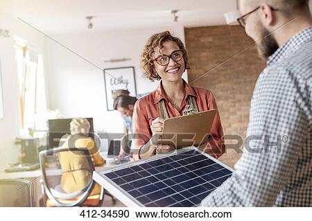 Stock Image - Smiling design professionals with blackboard and clipboard planning in office. Fotosearch