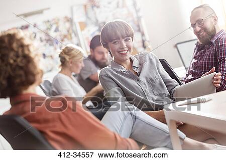 Stock Photo - Smiling design professionals with digital tablet meeting in office. Fotosearch