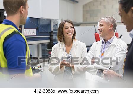 Stock Photography - Smiling engineers and managers in steel factory. Fotosearch