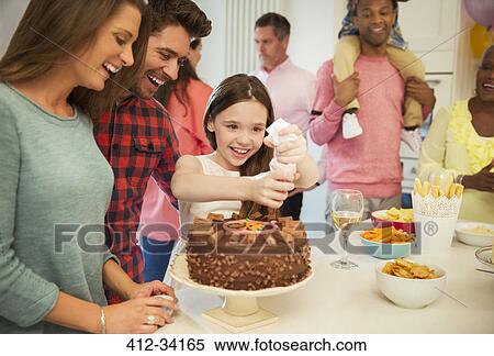 Smiling family icing chocolate cake in kitchen View Large Photo Image Stock Photography - Smiling family icing chocolate cake in kitchen. Fotosearch