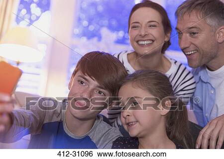 Stock Photograph - Smiling family taking selfie with camera phone. Fotosearch