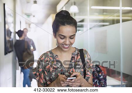 Smiling female college student texting in corridor View Large Photo Image Stock Image - Smiling female college student texting in corridor. Fotosearch