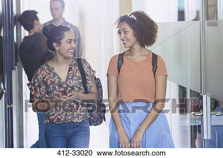 Smiling female college students walking in corridor View Large Photo Image Stock Image - Smiling female college students walking in corridor. Fotosearch