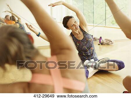 Smiling fitness instructor leading exercise class stretching arms View Large Photo Image Stock Photo - Smiling fitness instructor leading exercise class stretching arms. Fotosearch