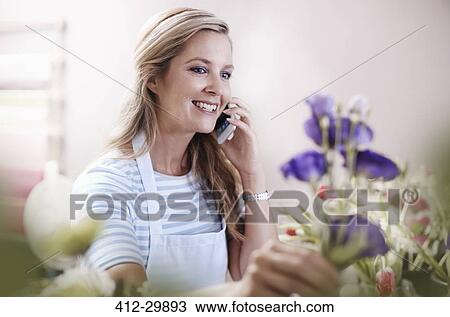 Smiling florist arranging flowers and talking on cell phone View Large Photo Image Stock Image - Smiling florist arranging flowers and talking on cell phone. Fotosearch