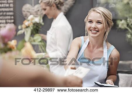 Stock Photo - Smiling florist being paid by customer in flower shop. Fotosearch