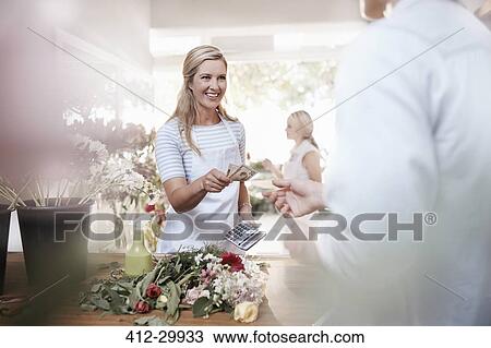 Smiling florist giving customer change in flower shop View Large Photo Image Stock Image - Smiling florist giving customer change in flower shop. Fotosearch